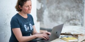 Frau in blauem T-Shirt mit Macbook